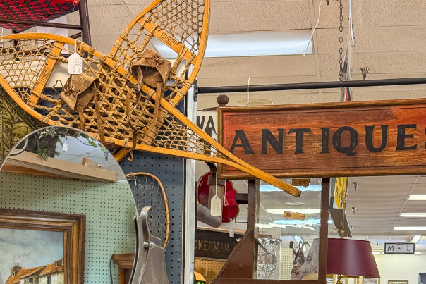 A wooden sign that reads "Antiques" hangs over a booth at Glenwood Antique Mall