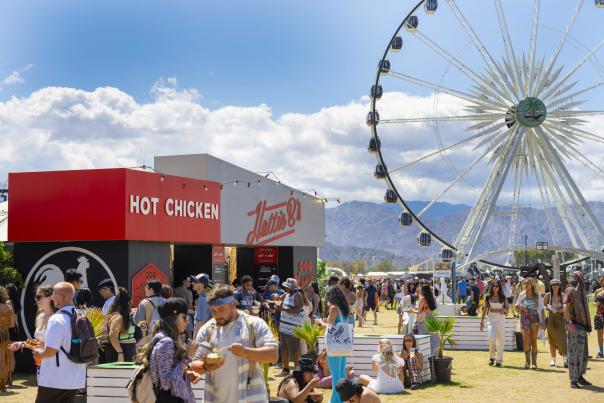 Lots of people stand around eating in front of the Hattie B's pop up restaurant at the Coachella Valley Music and Arts Festival.