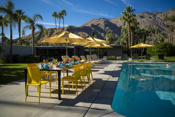 Poolside dining table with palm trees and mountains in the background