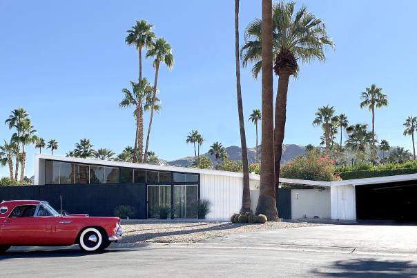 The outside of a Twin Palms neighborhood butterfly-roof home with a vintage car parked in front.