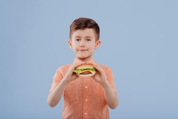child boy with sandwich in hand. looks at the camera,