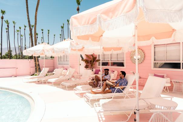 Two guys sitting in lounge chairs at the pink Trixie motel in Palm Springs