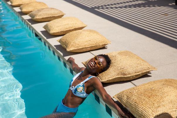 Black women lounging in the pool with head on a pillow.