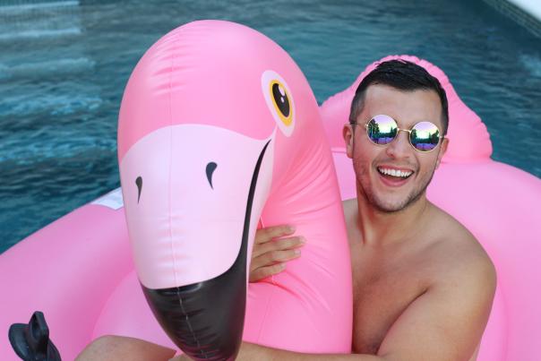 Man with inflatable flamingo in swimming pool