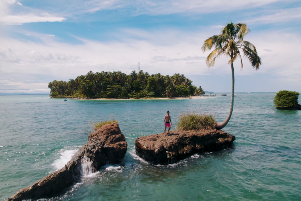 Man on a small island with one palm tree, near Cayo Zapatilla at Bocas del Toro