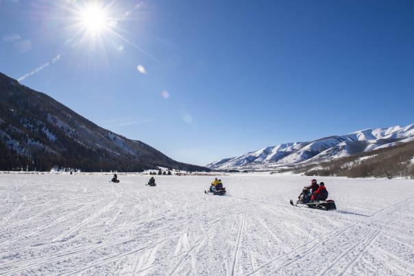 Group of snowmobiles in a wide-open field in Weber Canyon on sunny day.