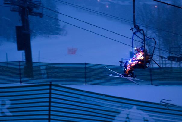 Skiers dressed in lights ride a chairlift at dusk near Park City, UT