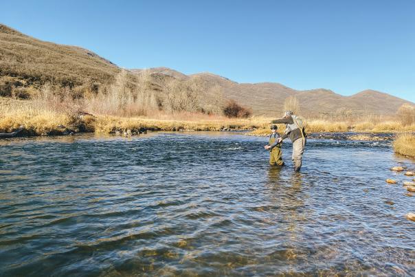 Instructor and student in the water learning fly fishing