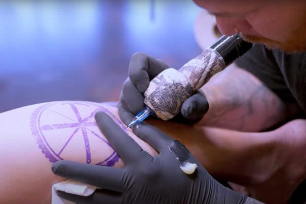 A tattoo artist tattoos a design on a leg at Latin Times Parlour in Park City, UT