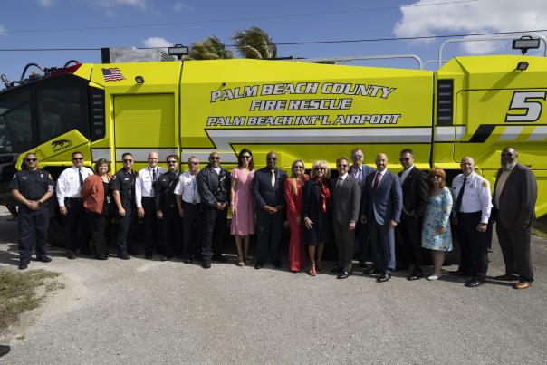 Group photo of Palm Beach County Fire Rescue personnel, Department of Airports staff, county commissioners, and county administration standing together in front of the department’s Dragon fire rescue truck.