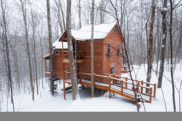 Treehouse cabin in the woods in Ohiopyle State Park covered in snow.