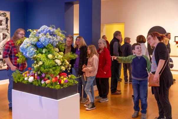 A group of people looking at a flower display in an art museum