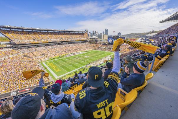 People in the stands of a football stadium waving yellow towels