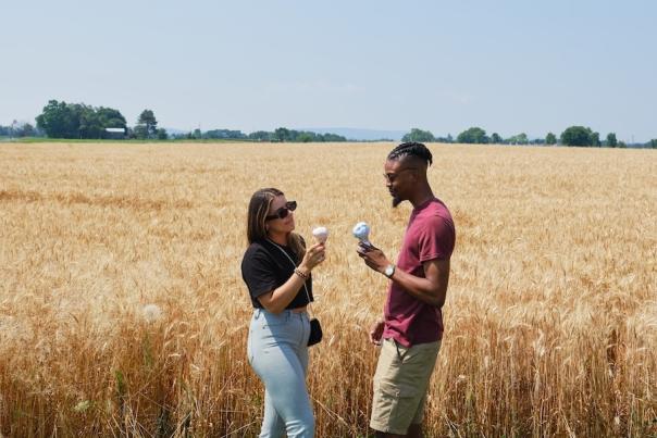 Two people eating ice cream cones in a field with tall grass