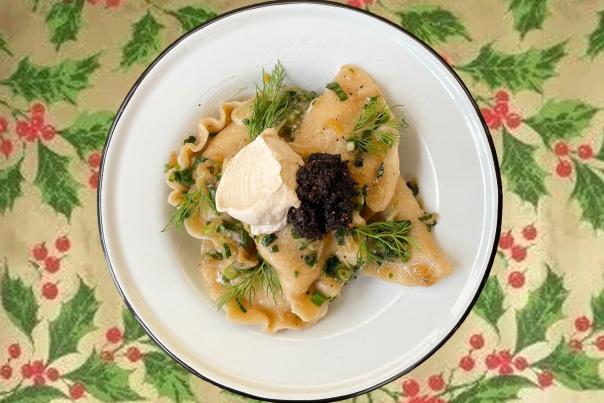 A plate of pierogies with garnish set on a decorative table cloth with holly