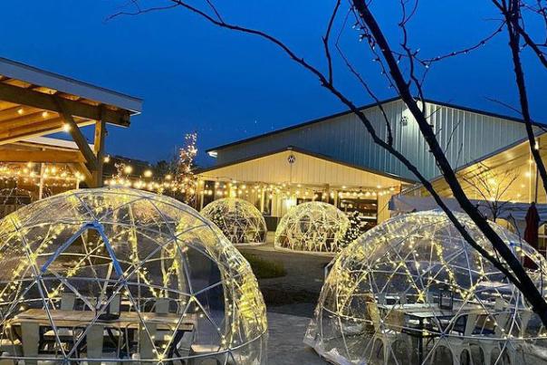 See through igloos over set tables on an outdoor patio with string lights