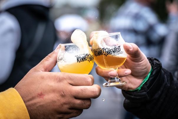 Two people cheersing glasses that read, "Kennett Square Brewfest"