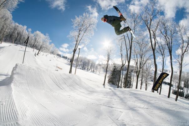 Person doing a trick on a snowboard in a terrain park at a ski resort