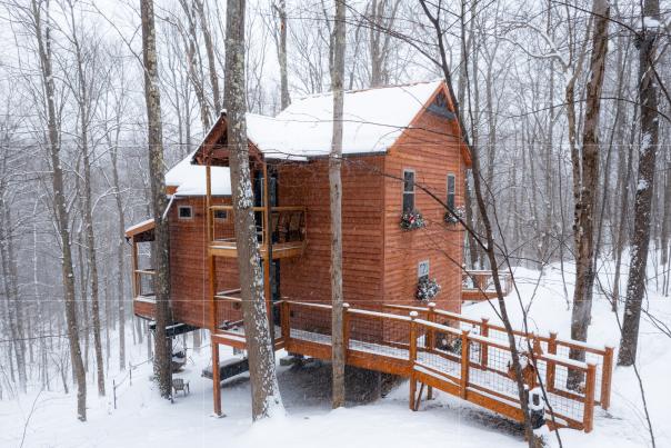 Treehouse cabin in the woods in Ohiopyle State Park covered in snow.