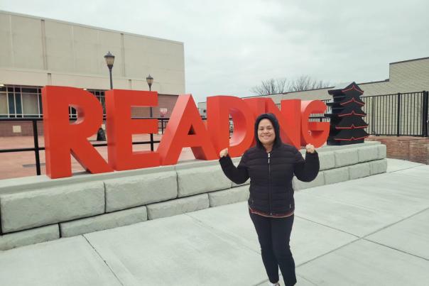 woman stands in front of the new art installation in downtown reading, featuring "Reading" and the pagoda.