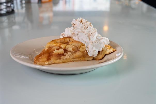A slice of apple pie with whipped cream dusted with cinnamon