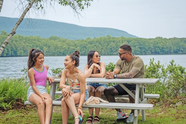 A family sits at a picnic table by the lake at Mountain Springs Lake Resort in the Poconos.
