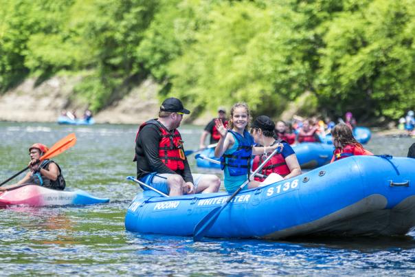 A little girl waves at the camera as a group enjoys whitewater rafting in the Pocono Mountains.