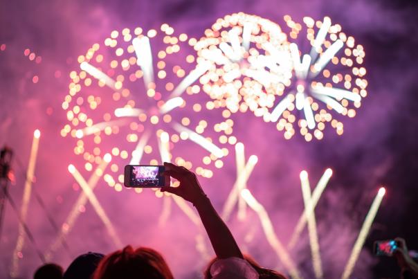 A crowd watches and photographs a beautiful fireworks display