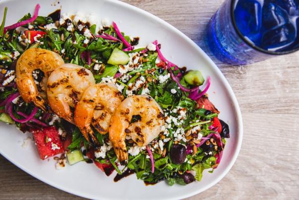 Four grilled shrimp atop a bed of greens with pickled beat shavings and chunks of Watermelon