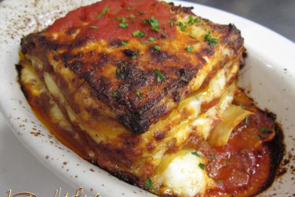 Lasagna slice in a white dish. The words Venetian Hot Plate in the bottom left corner