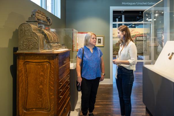 Two women face each other while standing in a museum.