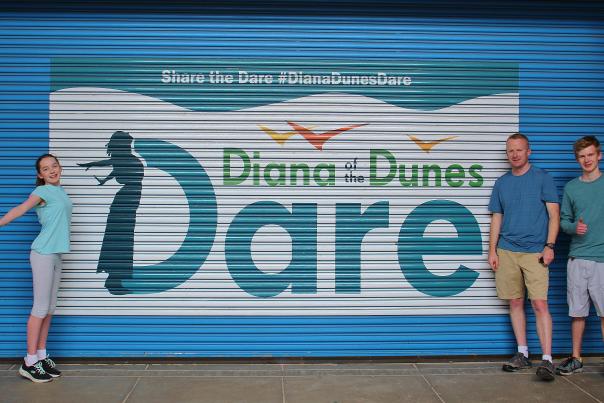 A family stands in front of a Diana Dunes Dare Mural
