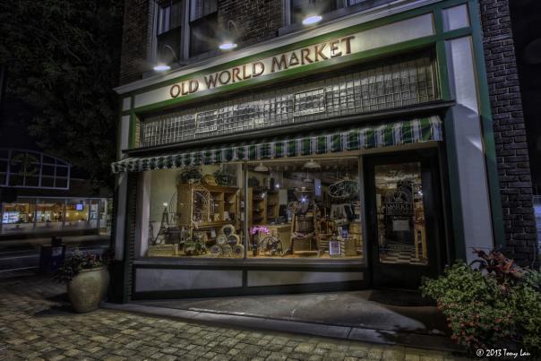 A nighttime shot of a storefront with "Old World Market" on the sign.