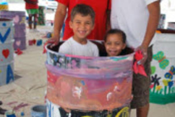 Image of a family of four in front of a painted oil drum.