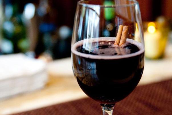 A glass of red wine with cinnamon sticks inside