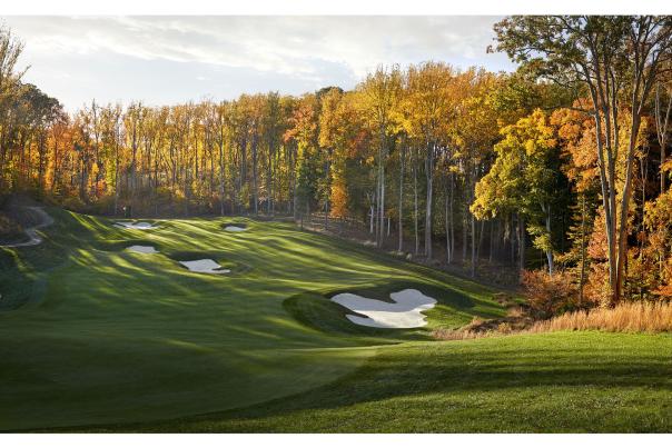 A golf course surrounded by trees with fall foliage