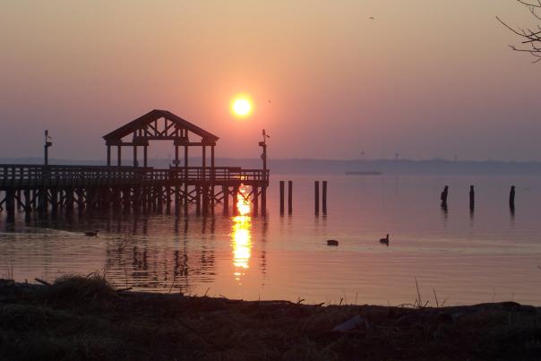a beach at sunset with a boardwalk in the background
