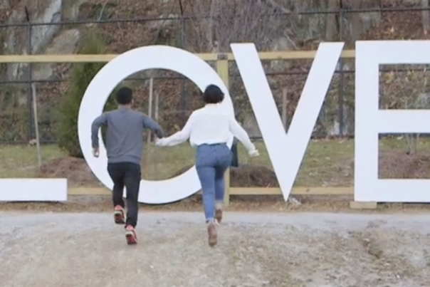 African American couple running towards LOVE sign