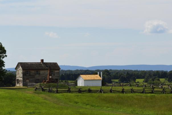 A field with a historic house in the background