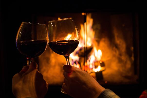Clinking wine glasses in front of fireplace