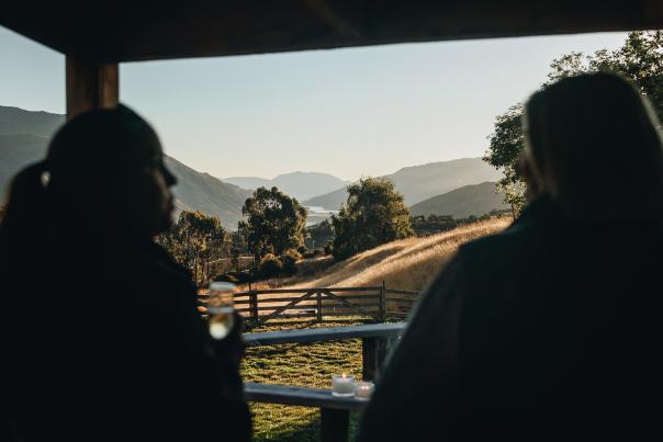 Siluete of two people talking and drinking champagne with rolling hills and sunset in the focus