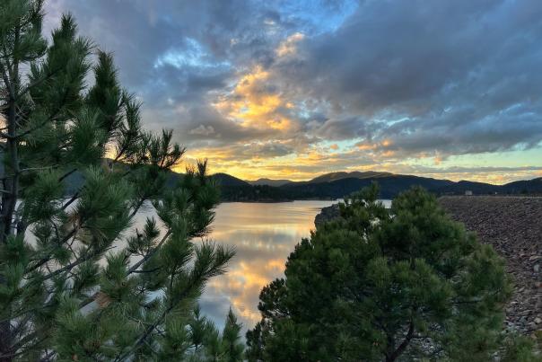 views of sunset at pactola lake through the trees in the black hills of south dakota