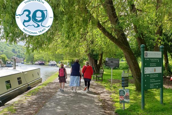 People walking along the Thames Path in Henley with boat moored