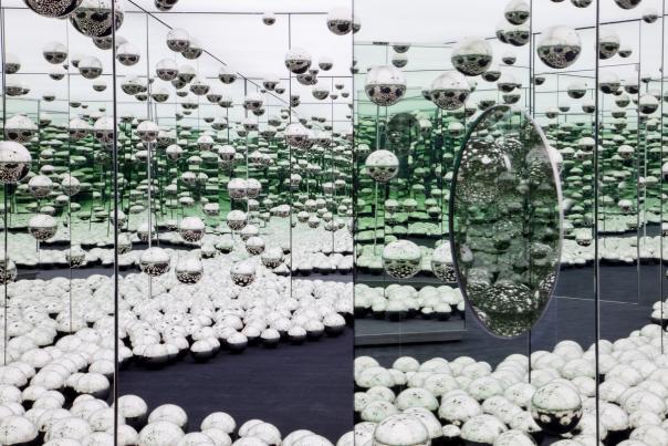 Photo of Yayoi Kusama Infinity Mirrored Room exhibit featuring mirrored walls, mirrored balls hanging from ceiling, and mirrored balls on the floor