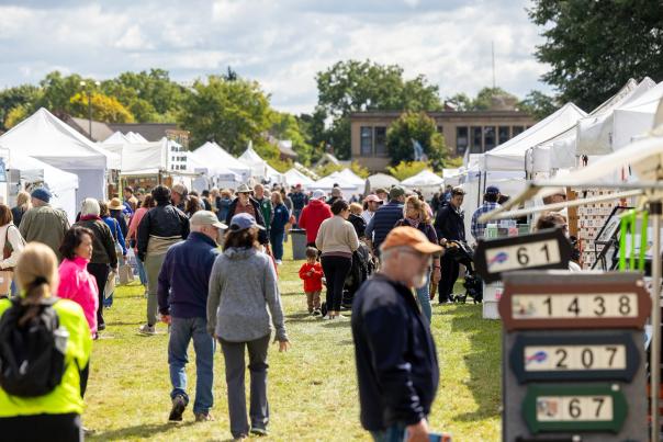 Visitors perusing the various pop-up booths filled with art and trinkets at the Clothesline Art Festival on the lawn of the Memorial Art Gallery.