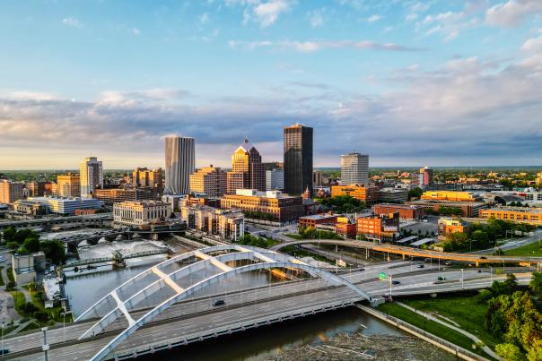 Photo of downtown Rochester, NY city skyline with sunset in left corner