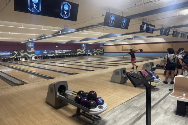Women bowler draws her arm back preparing to roll the ball down the lane