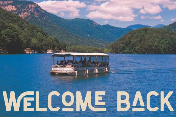 An image of a boat on Lake Lure with a text overlay that reads: Welcome Back to Rutherford.