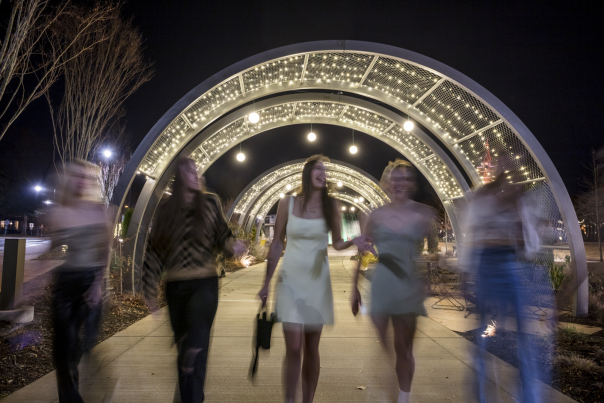 Girls walking through lit archways in park