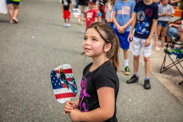 Girl holding American flag fan at the Faith 4th of July Celebration